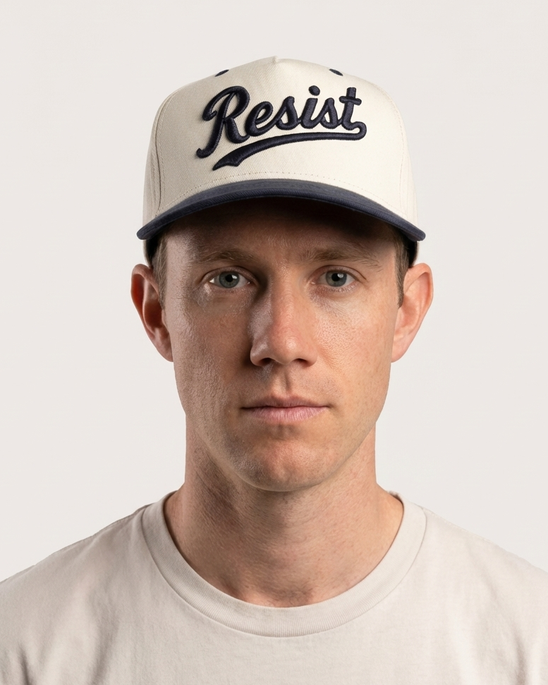 Man wearing a cap with 'Resist' text on a plain background